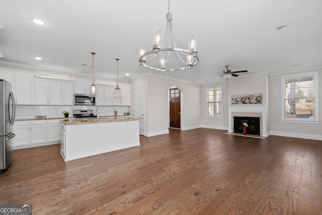 kitchen with hanging light fixtures, an island with sink, crown molding, and stainless steel appliances