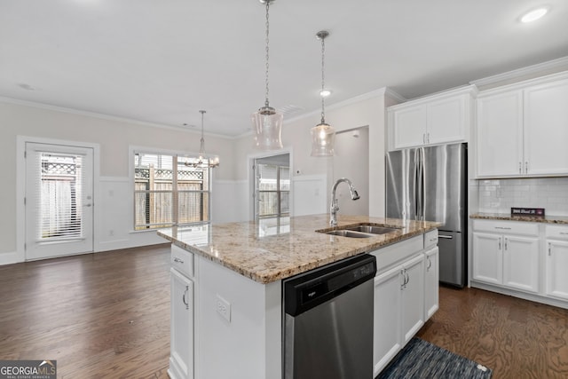 kitchen with a center island with sink, appliances with stainless steel finishes, decorative light fixtures, white cabinets, and sink