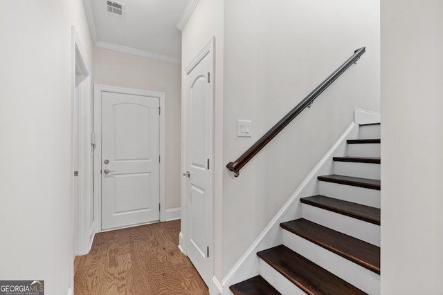 stairway with ornamental molding and hardwood / wood-style flooring