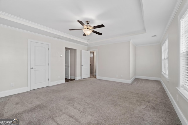 unfurnished bedroom with a raised ceiling, ceiling fan, crown molding, and carpet flooring