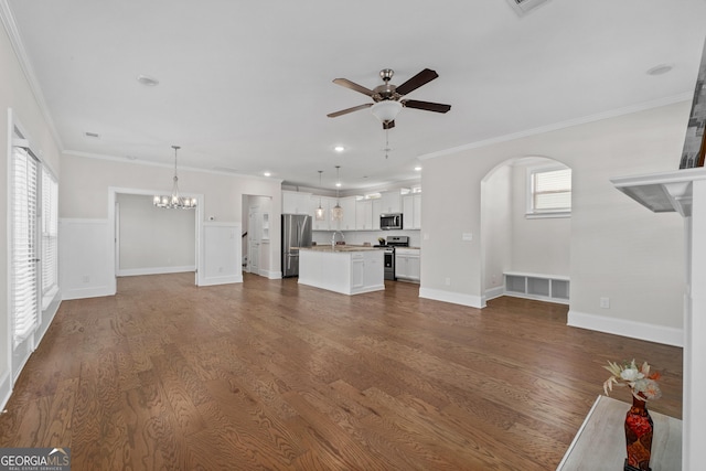 unfurnished living room with ceiling fan with notable chandelier, crown molding, and hardwood / wood-style flooring