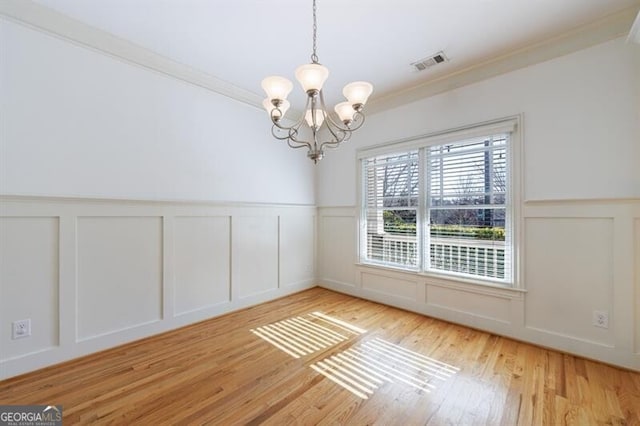 unfurnished room with crown molding, light hardwood / wood-style floors, and a chandelier