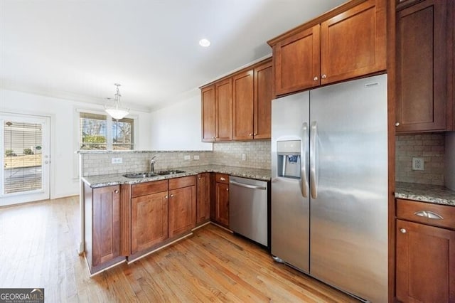 kitchen featuring light hardwood / wood-style floors, appliances with stainless steel finishes, sink, ornamental molding, and pendant lighting