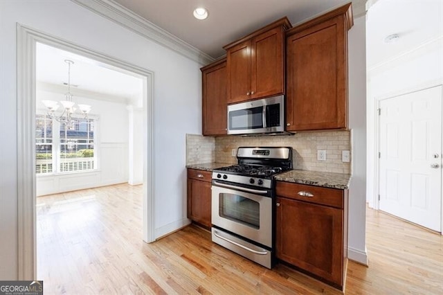 kitchen with stainless steel appliances, tasteful backsplash, ornamental molding, a chandelier, and stone counters