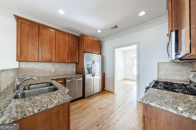 kitchen featuring appliances with stainless steel finishes, sink, backsplash, ornamental molding, and light stone counters