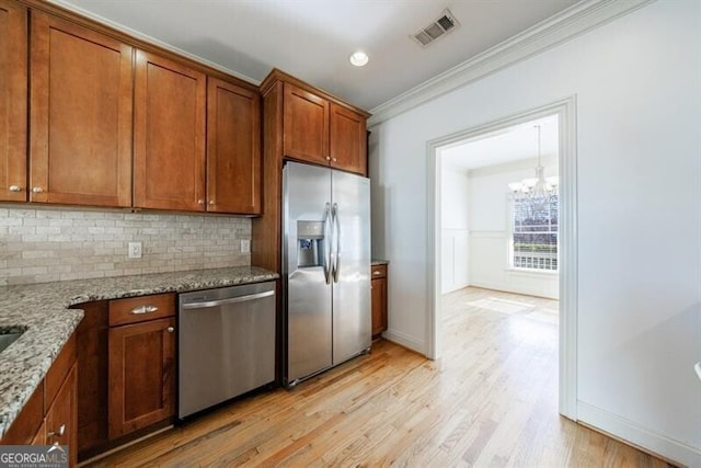 kitchen featuring light stone countertops, appliances with stainless steel finishes, light hardwood / wood-style floors, decorative backsplash, and crown molding