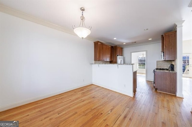 kitchen featuring pendant lighting, light hardwood / wood-style floors, refrigerator, ornamental molding, and kitchen peninsula