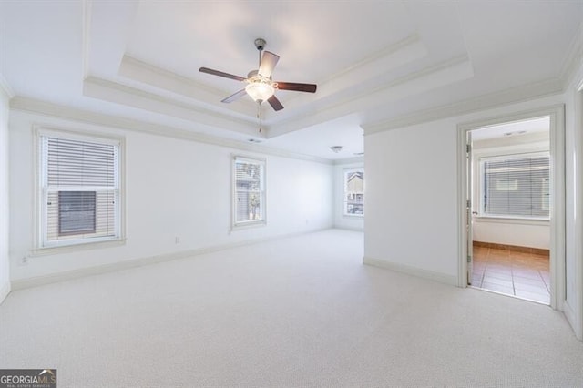 unfurnished room featuring ceiling fan, ornamental molding, light carpet, and a tray ceiling