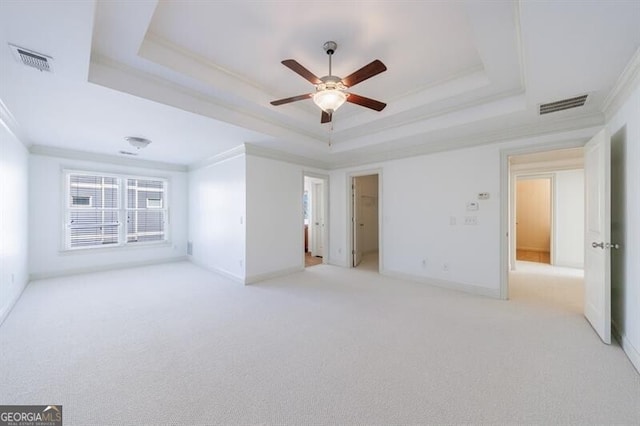 carpeted empty room featuring ceiling fan, a tray ceiling, and ornamental molding