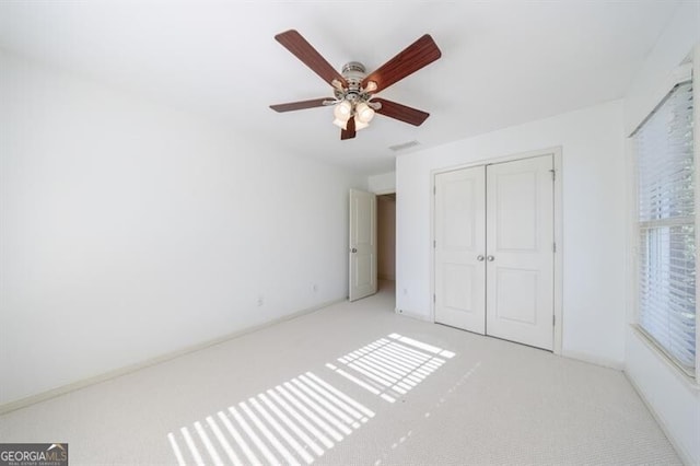 unfurnished bedroom with ceiling fan, light colored carpet, and a closet