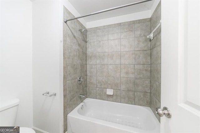 bathroom featuring tiled shower / bath combo and toilet