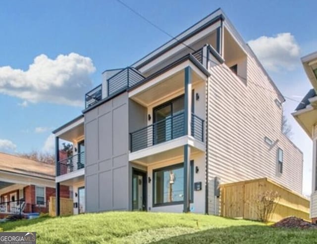 view of front of home with a balcony, stairway, and stucco siding