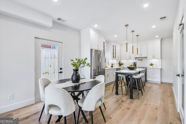 dining area with light wood-type flooring, visible vents, and recessed lighting