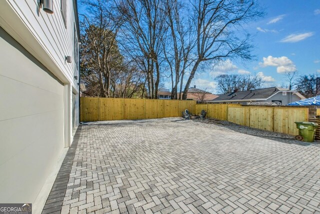 view of side of property with decorative driveway, fence, and an attached garage