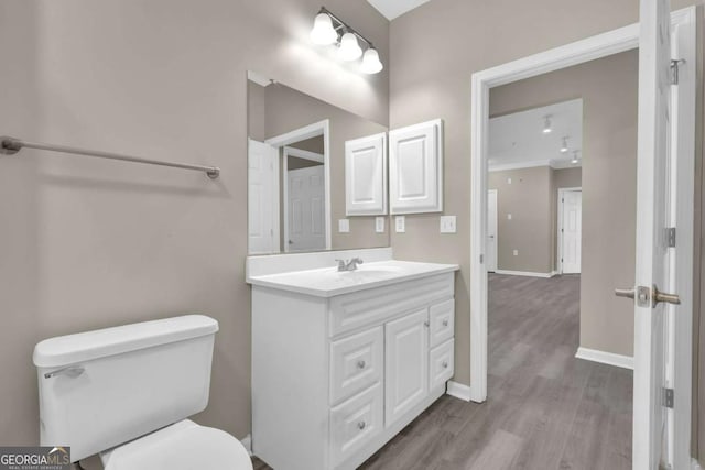 bathroom featuring wood-type flooring, toilet, and vanity