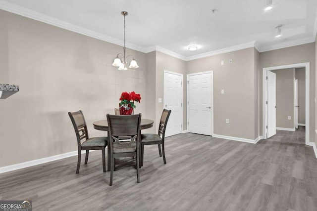 dining room with hardwood / wood-style floors, crown molding, and a chandelier