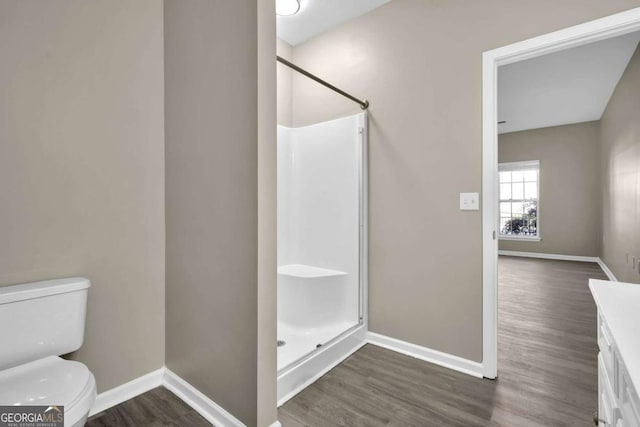 bathroom with hardwood / wood-style flooring, toilet, walk in shower, and vanity