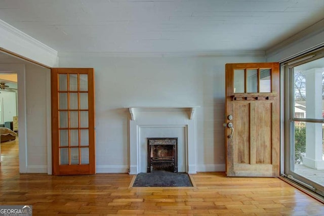 unfurnished living room featuring ornamental molding, light hardwood / wood-style floors, and french doors