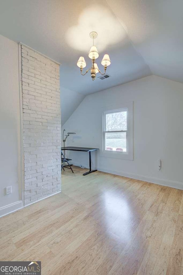 bonus room featuring lofted ceiling, a notable chandelier, and light hardwood / wood-style floors