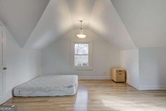 bedroom featuring light wood-type flooring and vaulted ceiling