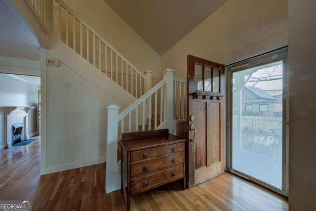 foyer entrance with wood-type flooring and vaulted ceiling