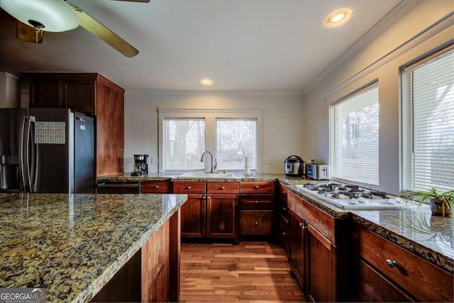 kitchen with light hardwood / wood-style floors, sink, black fridge with ice dispenser, light stone counters, and gas stovetop