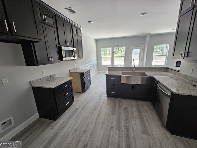 kitchen featuring decorative light fixtures, sink, light hardwood / wood-style flooring, light stone countertops, and stainless steel appliances