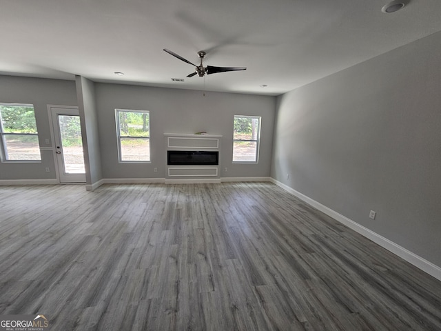 unfurnished living room featuring ceiling fan, a wealth of natural light, and wood-type flooring