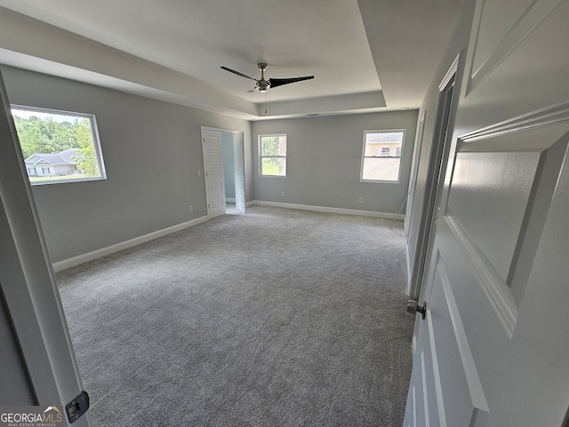 carpeted empty room featuring ceiling fan and a tray ceiling