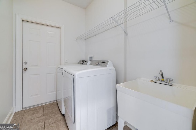 laundry area featuring light tile patterned floors, washer and dryer, and sink