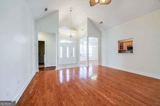 foyer with ceiling fan with notable chandelier, light hardwood / wood-style floors, and high vaulted ceiling