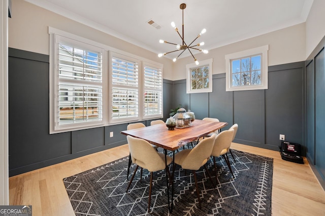 dining area featuring ornamental molding, a chandelier, and light hardwood / wood-style floors