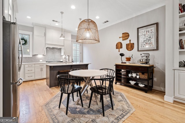 dining area featuring crown molding and light wood-type flooring