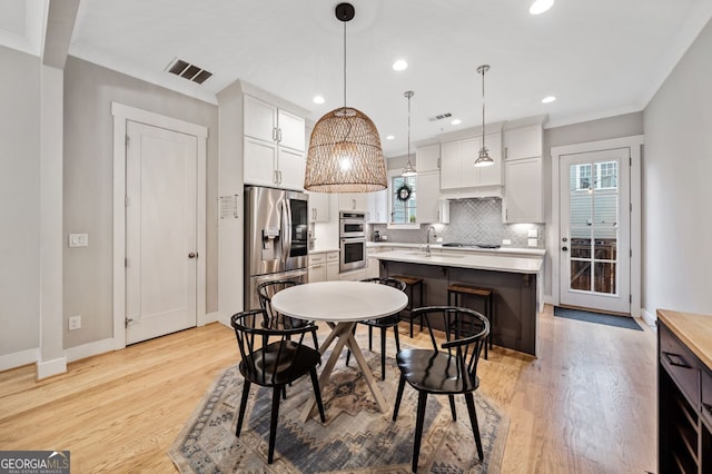 dining area featuring crown molding, sink, and light wood-type flooring