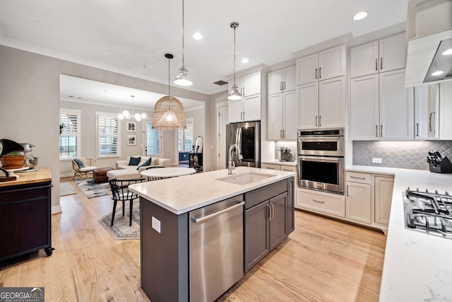 kitchen featuring sink, light stone counters, hanging light fixtures, stainless steel appliances, and white cabinets