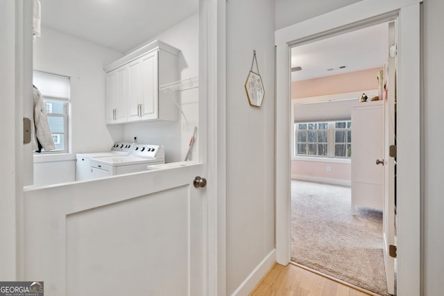 washroom featuring cabinets, light hardwood / wood-style floors, and washer and dryer