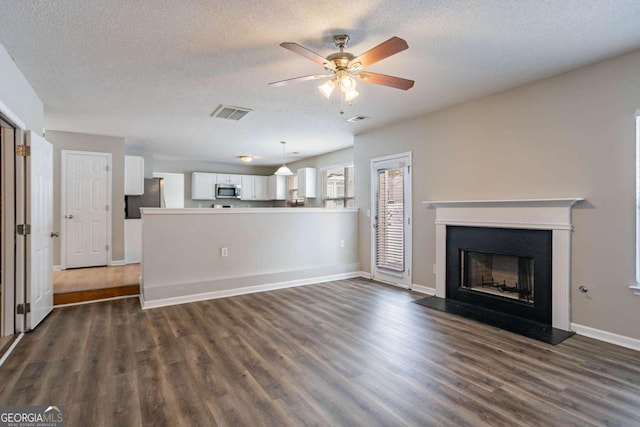 unfurnished living room with ceiling fan, dark hardwood / wood-style flooring, and a textured ceiling