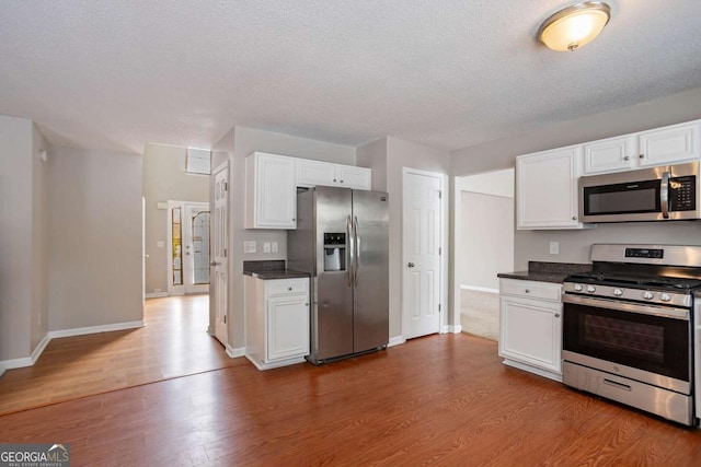 kitchen featuring wood-type flooring, white cabinets, and stainless steel appliances