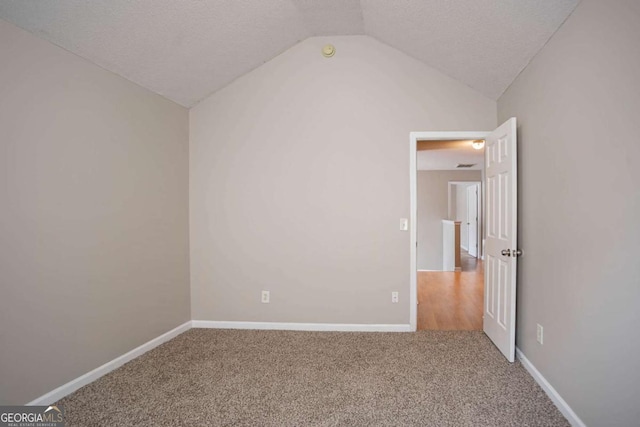 unfurnished bedroom featuring carpet floors, a textured ceiling, and vaulted ceiling