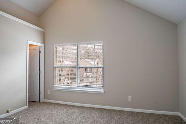 empty room with vaulted ceiling and carpet flooring