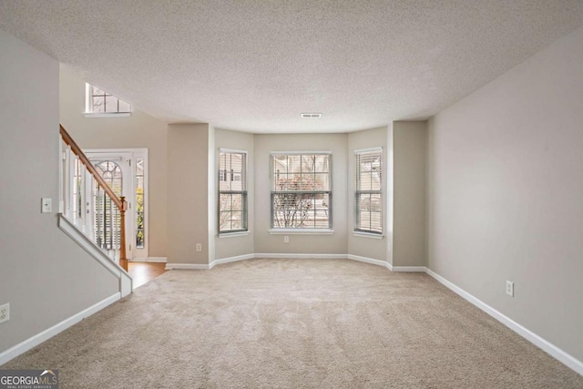 empty room with light colored carpet and a textured ceiling