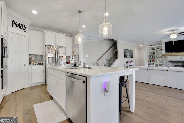 kitchen featuring sink, white cabinetry, hanging light fixtures, an island with sink, and stainless steel appliances