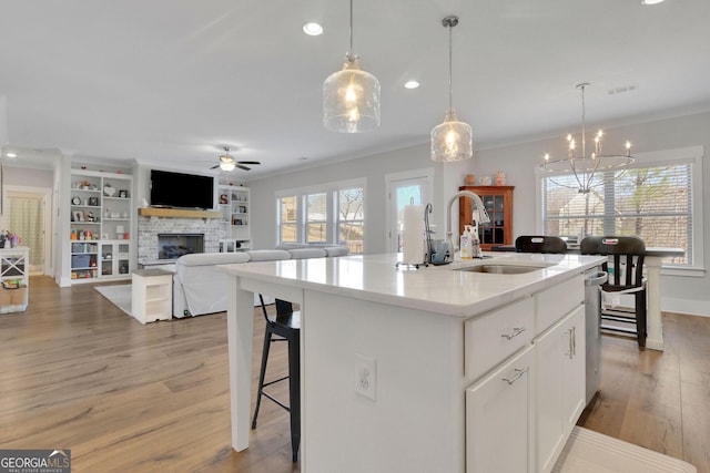 kitchen with sink, crown molding, white cabinets, and a center island with sink