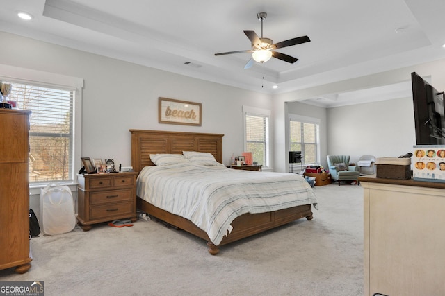 carpeted bedroom featuring a tray ceiling and ceiling fan