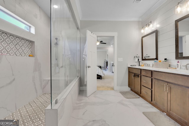 bathroom with crown molding, ceiling fan, vanity, and a tile shower