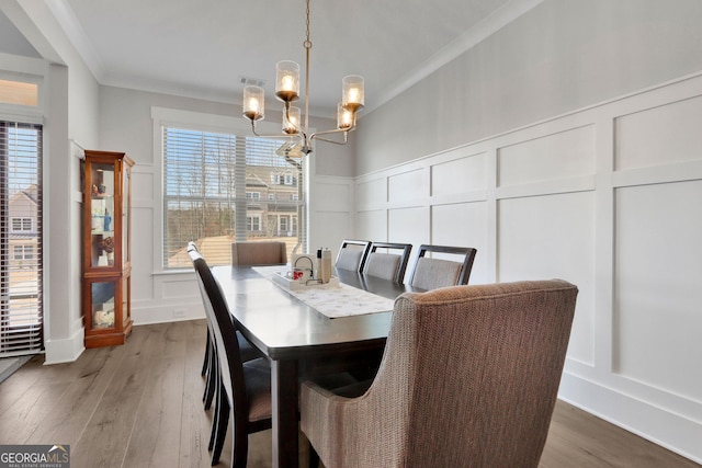 dining space with crown molding, a healthy amount of sunlight, hardwood / wood-style floors, and a notable chandelier