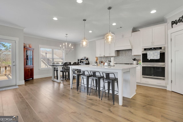 kitchen with hanging light fixtures, white cabinetry, and premium range hood