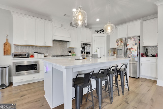 kitchen with hanging light fixtures, white cabinets, and appliances with stainless steel finishes