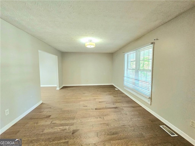 unfurnished room with a textured ceiling and hardwood / wood-style floors