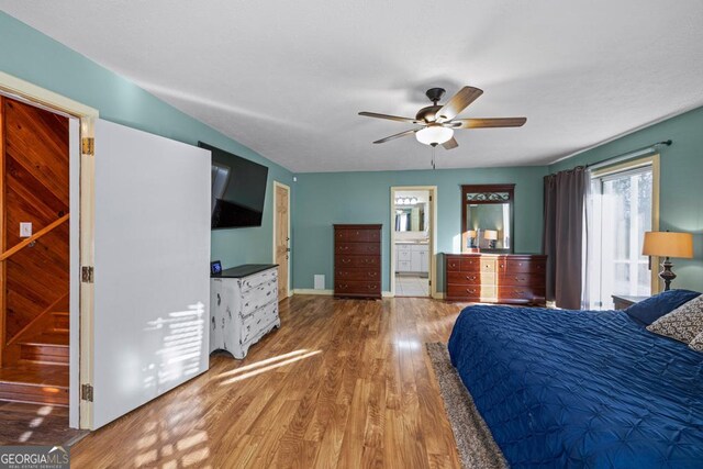 bedroom with ceiling fan, a textured ceiling, ensuite bathroom, and light wood-type flooring